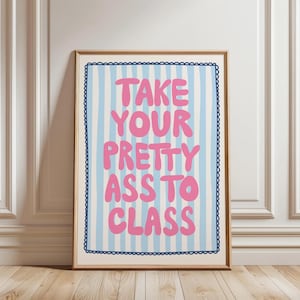May include: A framed art print with the text "TAKE YOUR PRETTY ASS TO CLASS" in pink, set against a light blue and white striped background. The print has a dark blue scalloped border and a wooden frame.