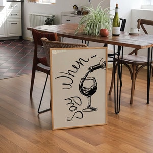 K&ouml;nnte beinhalten: Ein gerahmter Druck mit einer Schwarzwei&szlig;illustration eines Weinglases, in das eine Flasche Wein gef&uuml;llt wird. Der Text "Say When..." ist in einer kursivschriftlichen Schriftart &uuml;ber dem Glas geschrieben.