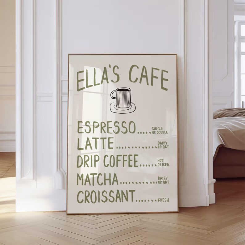 Puede incluir: Un p&oacute;ster enmarcado con el texto "ELLA'S CAFE" en verde, que enumera opciones de caf&eacute; y pasteler&iacute;a. El men&uacute; incluye espresso, latte, caf&eacute; de goteo, matcha y croissant. Un sencillo dibujo lineal de una taza de caf&eacute; est&aacute; en la parte superior.