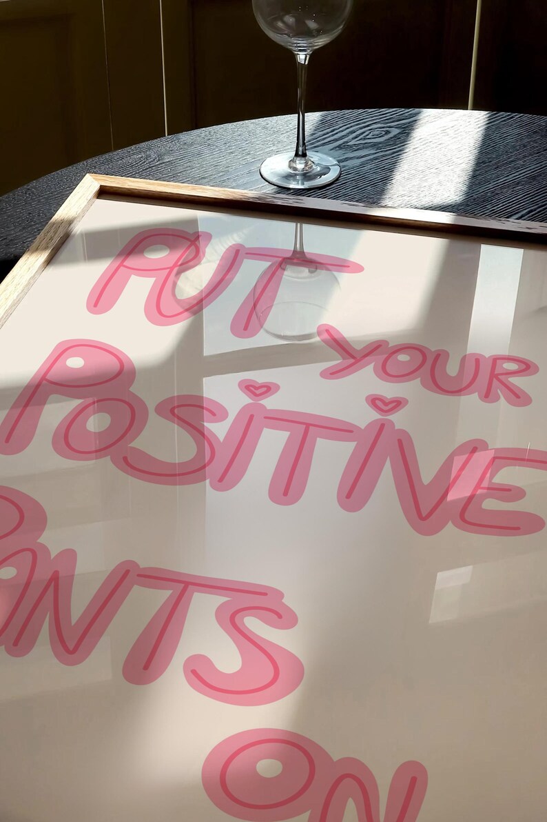 May include: A framed print with the text "Put your positive pants on" in pink lettering on a white background.