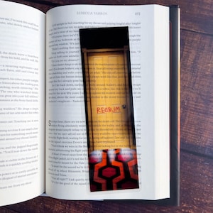 May include: A red and black bookmark with a graphic of a door with the word "REGIUM" written on it. The door has a pattern of red and black squares.