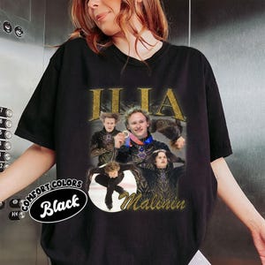 May include: Black Comfort Colors t-shirt featuring a collage of images of Ilia Malinin, with gold glitter text that reads "ILIA" and "Malinin". The shirt also has a circular graphic that says "Comfort Colors Black".
