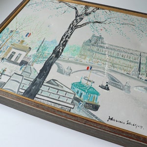 May include: A framed painting depicting a Parisian cityscape with a bridge, buildings, and a boat on the Seine River. The painting is signed "Johannes Seiliger" in the lower right corner.
