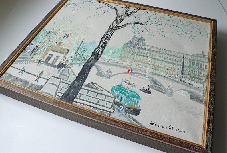 May include: A framed painting depicting a Parisian cityscape with a bridge, buildings, and a boat on the Seine River. The painting is signed "Johannes Seiliger" in the lower right corner.
