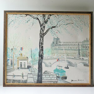 May include: A framed painting depicting a Parisian scene with a bridge, a building, and a tree. The painting is done in a light blue, green, and white color palette. The artist's signature is visible in the bottom right corner.