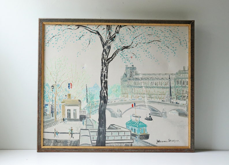 May include: A framed painting depicting a Parisian scene with a bridge, a building, and a tree. The painting is done in a light blue, green, and white color palette. The artist's signature is visible in the bottom right corner.