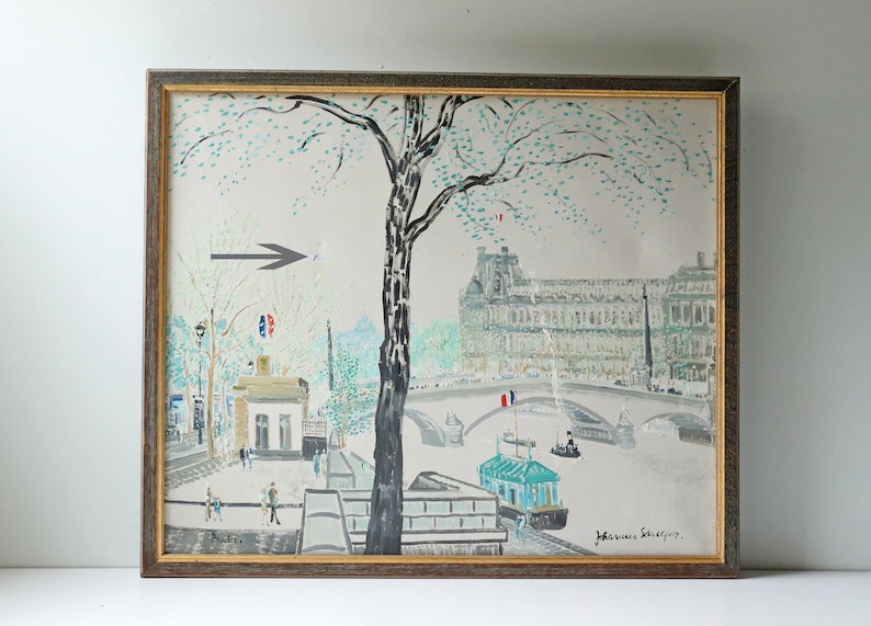 May include: A framed painting depicting a Parisian scene with a bridge, a river, and buildings. The painting is done in a light, impressionistic style with a focus on the buildings and the bridge. The painting is signed "Jean-Pierre Schnyder" in the lower right corner.