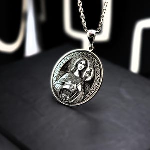 A silver pendant necklace with an oval-shaped medallion featuring a woman's portrait.