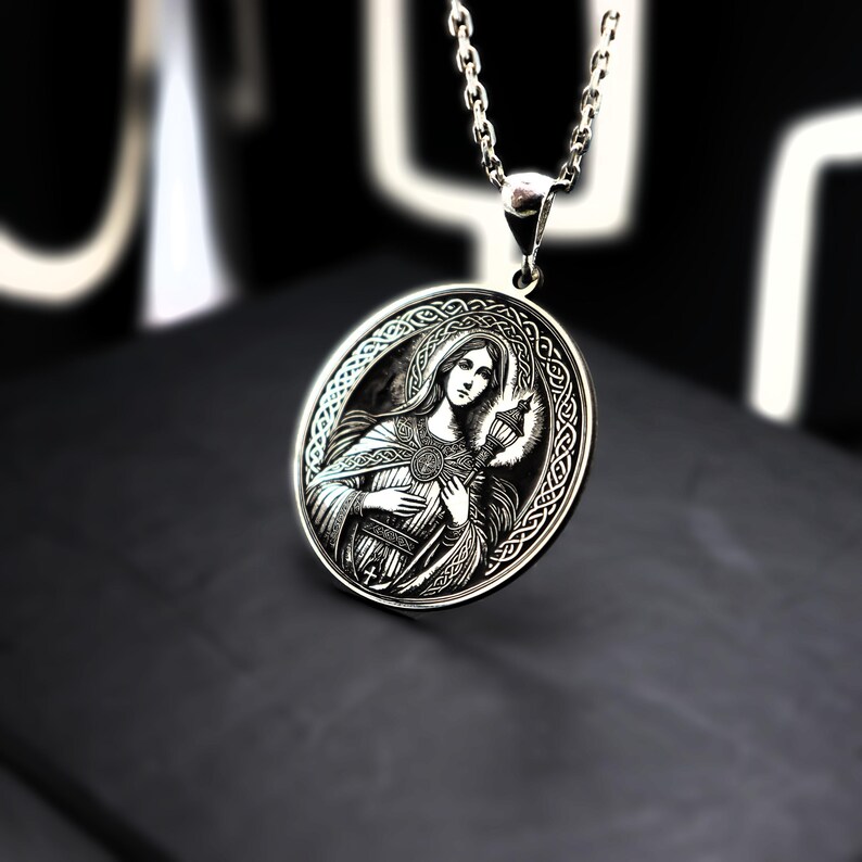 A silver pendant necklace with an oval-shaped medallion featuring a woman's portrait.