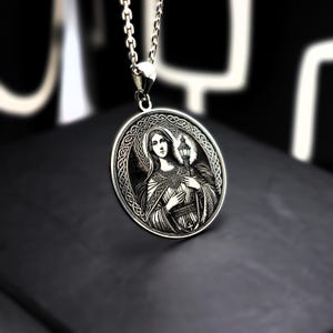 A silver pendant necklace with a circular medallion featuring an image of a woman.