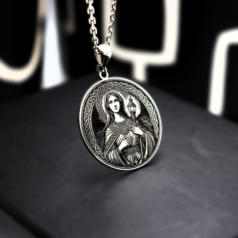 A silver pendant necklace with a circular medallion featuring an image of a woman.