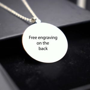 May include: A silver necklace with a round pendant that says "Free engraving on the back".