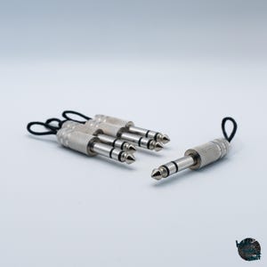 May include: Several silver 1/4 inch audio jacks with black loops. The jacks have a textured grip and a pointed tip. The jacks are used for connecting audio equipment.