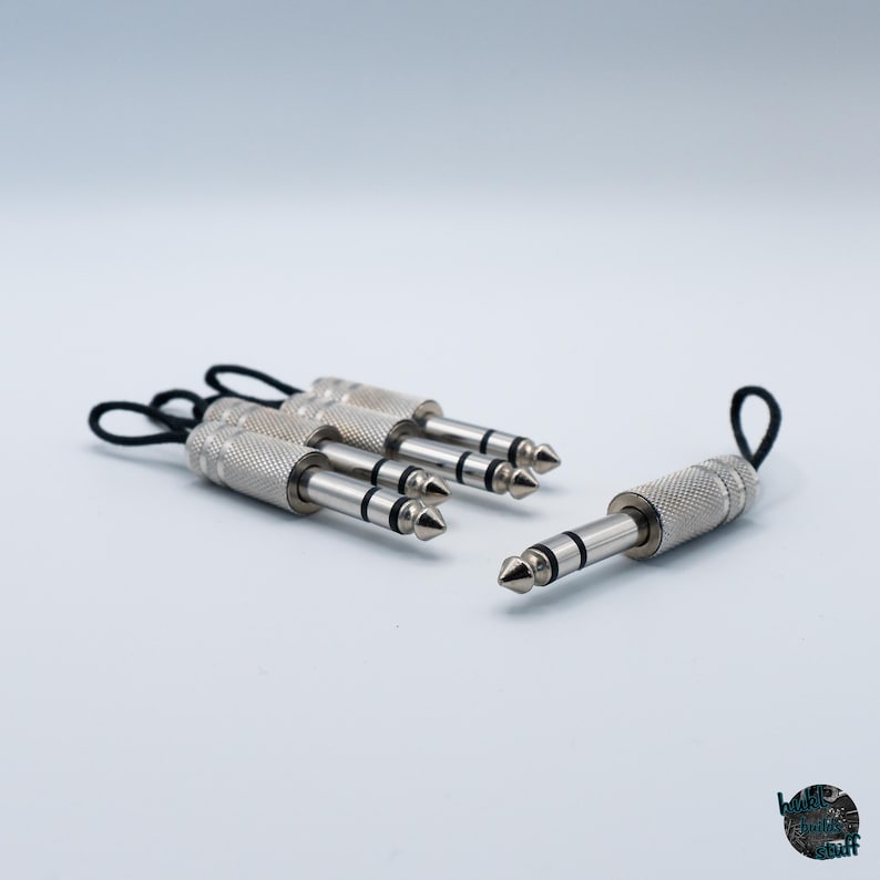 May include: Several silver 1/4 inch audio jacks with black loops. The jacks have a textured grip and a pointed tip. The jacks are used for connecting audio equipment.