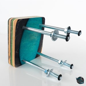 Könnte beinhalten: Ein tealblauer und mehrfarbiger Skateboard-Deck-Hocker mit drei Metallstangen und Muttern. Der Hocker ist aus recycelten Skateboards hergestellt.