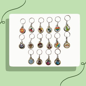 May include: Twenty wooden keychains with colorful cross-stitch designs. The keychains feature various characters and symbols, including a mushroom, a rainbow, a heart, a cherry, a star, a dinosaur, a video game character, and a cat.