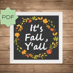 May include: A black and white cross-stitch pattern with a wreath of fall leaves and the text "It's Fall, Y'all".