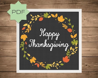 May include: Cross stitch pattern featuring a wreath of autumn leaves and the text "Happy Thanksgiving" on a black background.