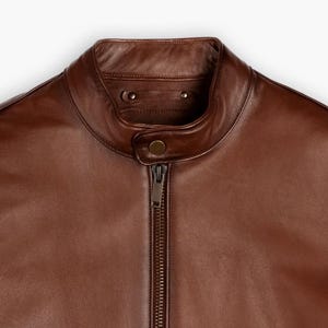 May include: A brown leather motorcycle jacket with a zipper closure and a stand-up collar.
