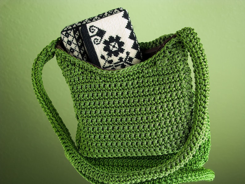 Pu&ograve; includere: Una borsa a tracolla in crochet verde con una pochette in tessuto a motivi bianco e nero all'interno.