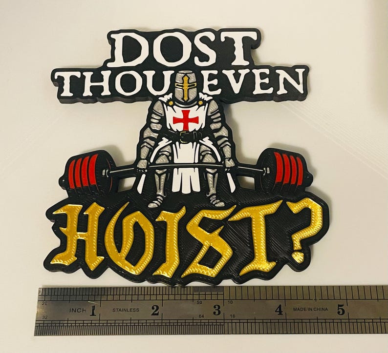 Pu&ograve; includere: Una toppa grafica nera, bianca, rossa e oro raffigurante un cavaliere in armatura che solleva un bilanciere con pesi rossi. Il testo recita DOST THOU EVEN HOIST? Un righello in acciaio inox mostra una larghezza di circa 12,7 cm.