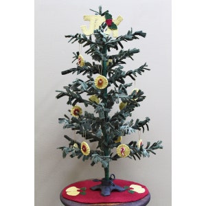May include: A small artificial Christmas tree decorated with felt ornaments. The ornaments are yellow with red centers and a few have candy canes. The tree is topped with a felt "JOY" sign.