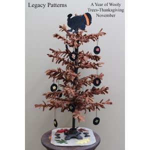 May include: A brown felt Christmas tree with a black felt turkey on top. The tree is decorated with black felt ornaments and is sitting on a brown table with a felt rug.