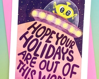 May include: A pink and purple greeting card with a cartoon alien in a flying saucer. The card reads "Hope your holidays are out of this world!"