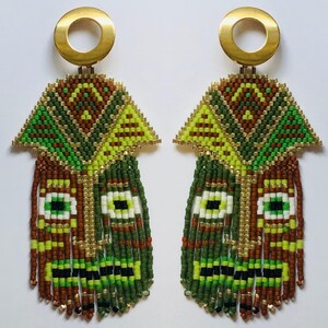 May include: A pair of green, brown, and gold beaded earrings with a geometric pattern and fringe. The earrings are made with small beads and have a gold metal hook.