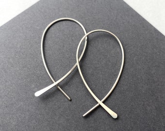 May include: A pair of silver hoop earrings with a unique fishtail design.