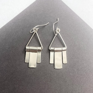 May include: Silver dangle earrings with a triangular top and multiple rectangular pendants.