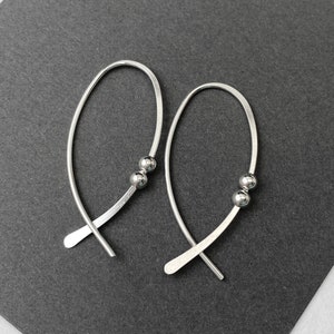 May include: A pair of silver hoop earrings with a small silver ball at the end of each hoop.