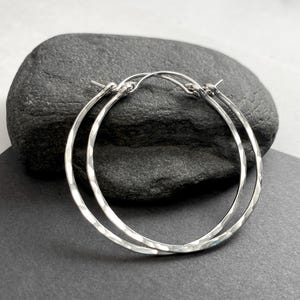 May include: A pair of silver hammered hoop earrings. The earrings are simple and elegant, and they would make a great gift for any occasion.