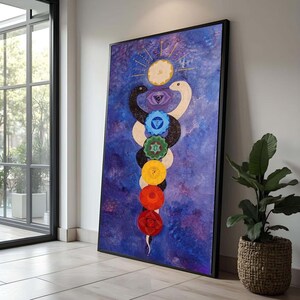 May include: A large framed painting featuring a stylized depiction of a Kundalini serpent with seven chakra symbols. The artwork is set against a textured blue background, with a sun symbol at the top. The painting is leaning against a white wall.
