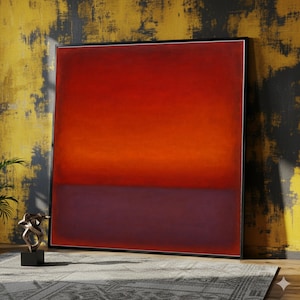 Puede incluir: Gran pintura abstracta con un degradado de tonos rojos y naranjas en la parte superior, que transiciona a un púrpura profundo en la parte inferior. La obra de arte está enmarcada en un borde negro y se apoya contra una pared texturizada amarilla y negra.