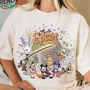May include: A white t-shirt with a colorful graphic print of Mickey Mouse and other Disney characters celebrating Halloween at Epcot. The graphic includes the Epcot logo and a variety of Halloween-themed imagery.