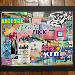 May include: A mixed media collage in a black frame. The artwork features various stickers, including dinosaurs, question marks, and the word "FUCK". A Modelo beer can is visible, along with the text "LARGE SIZE" and "SEE ACT II".