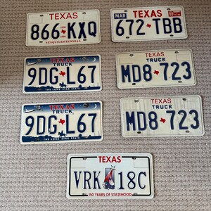 May include: A collection of vintage Texas license plates. The plates feature the word "TEXAS" at the top, with various alphanumeric combinations and the iconic Texas star. Some plates include the text "TRUCK" and "THE LONE STAR STATE".