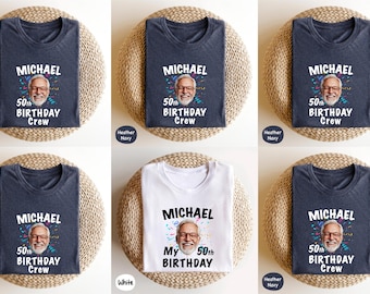 May include: A collection of heather navy and white t-shirts. Each shirt features a graphic with the name "MICHAEL", a portrait, and the text "50th BIRTHDAY Crew" or "My 50th BIRTHDAY". The shirts are displayed on round woven mats.