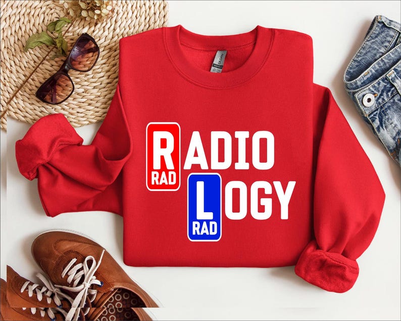 以下が含まれることがあります： 白い文字で「RADIOLOGY」と書かれた赤いスウェットシャツ。文字の両側に青い正方形で「RAD」と書かれている。
