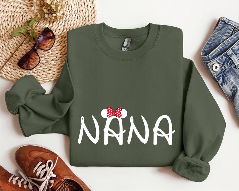 May include: A green sweatshirt with a white graphic of the word "NANA" with a red and white bow on top of the first letter.