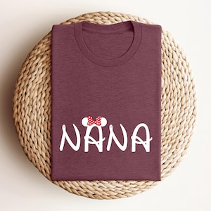 May include: Burgundy t-shirt with a white graphic of a cartoon mouse with a red bow and the word "NANA" in white.