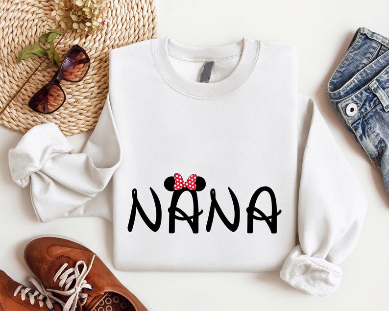 May include: White sweatshirt with a black and red Mickey Mouse inspired design that says "NANA" in a playful font.