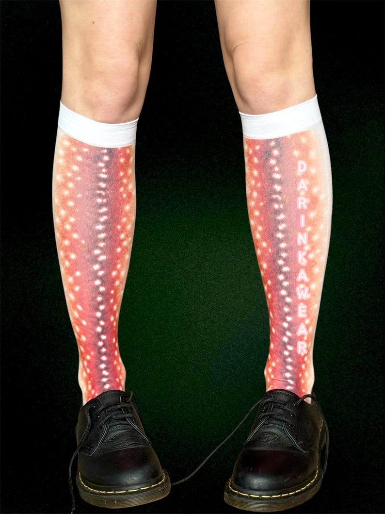 May include: Knee-high socks with a red and white spotted pattern, resembling a fish. The socks have a white band at the top and the word "DARINKAWEAR" printed vertically. Black leather shoes are worn with the socks.