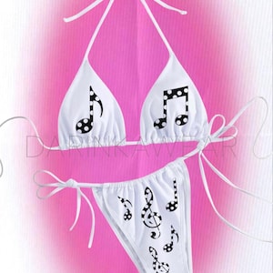 Könnte beinhalten: Weißes Bikini-Set mit Noten-Design. Das Neckholder-Top und der Slip sind mit schwarzen Noten mit Tupfen verziert. Das Bikini hat weiße Bindebänder und ist vor einem rosa Hintergrund platziert.