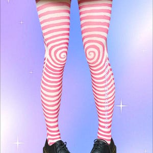 May include: Pink and white striped thigh-high stockings with a spiral design, paired with black leather shoes. The stockings have the text "KAWAIIWEAR" printed vertically on the side. The background is a gradient of purple and blue.