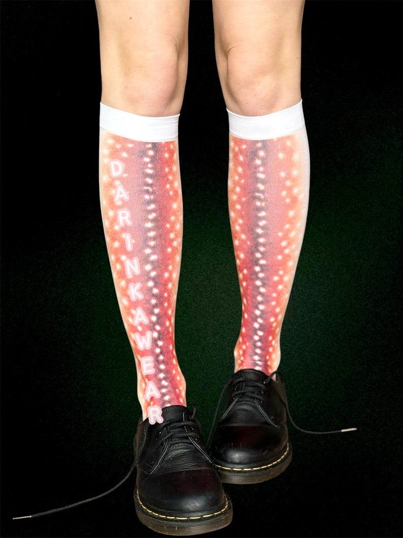 May include: Knee-high socks with a red and white spotted design, and the word "DARKWEAR" in white. The socks are worn with black leather shoes. The background is dark green.