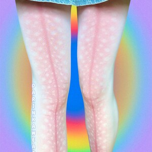 May include: White tights featuring a pink deer-like pattern with white spots and a vertical pink stripe running down the center of each leg. The text DARINKAWEAR is printed vertically in white letters on the side of the right leg below the knee.