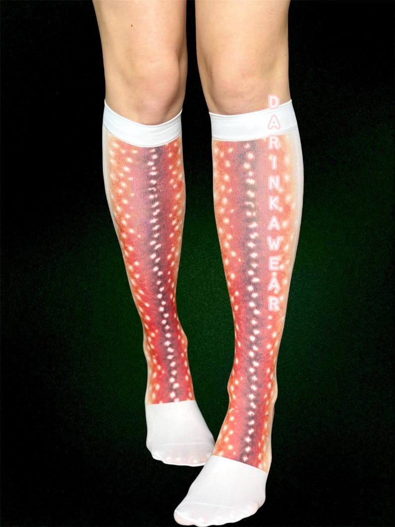 May include: Knee-high socks featuring a deer-like pattern in red, purple, and white. The socks have white cuffs and foot sections. The word "DRINKAWEAR" is printed vertically on the side of the socks.
