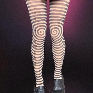 Könnte beinhalten: Schwarz-beige gestreifte Strumpfhose mit einem Spiralmuster an den Knien. Das Wort "DARLING" ist vertikal auf die Strumpfhose gedruckt. Die Person trägt schwarze Lederschuhe und einen schwarzen Rock.